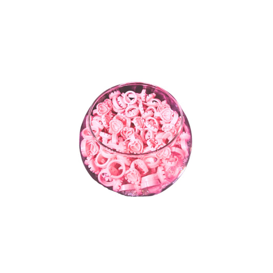 Bowl of disposable pink lash glue rings on a white background