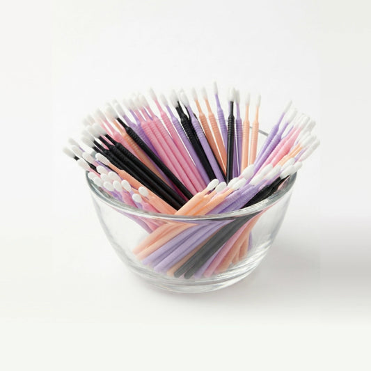 Glass bowl filled with colorful microswabs on a white background