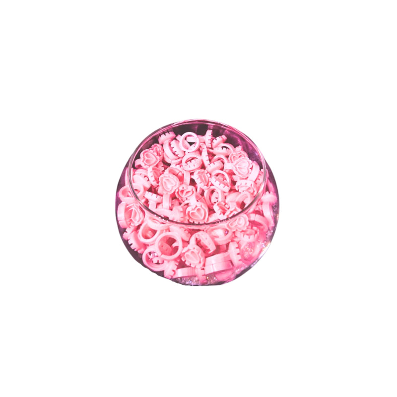 Bowl of disposable pink lash glue rings on a white background